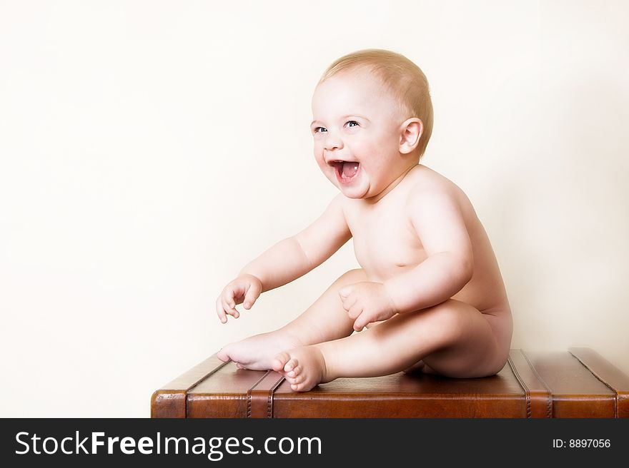 Young baby sitting on an old style suitcase