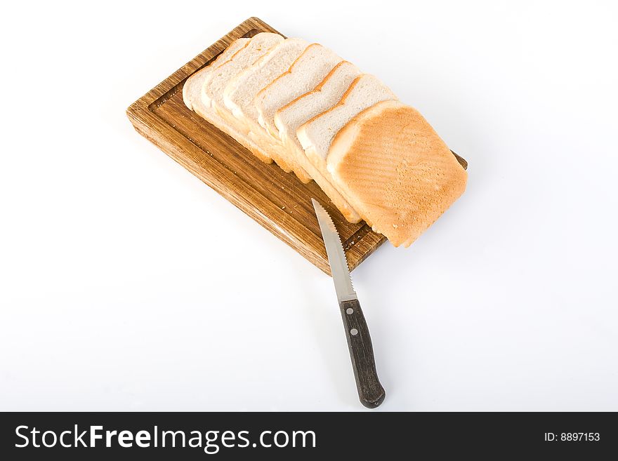 Picture of a white bread loaf sliced on a brown board. Picture of a white bread loaf sliced on a brown board