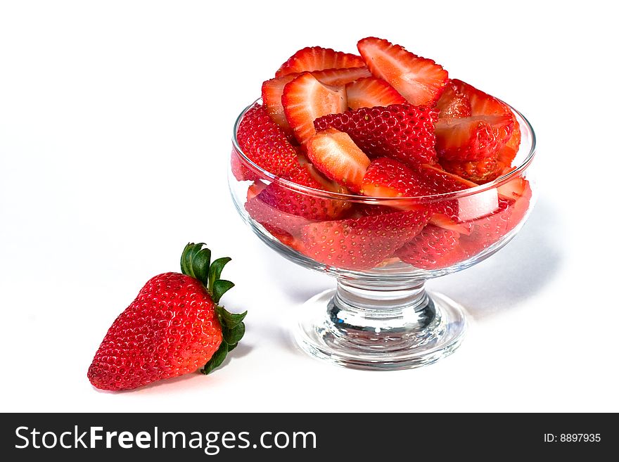 Fresh strawberry next to bowl of cut strawberries. Fresh strawberry next to bowl of cut strawberries.