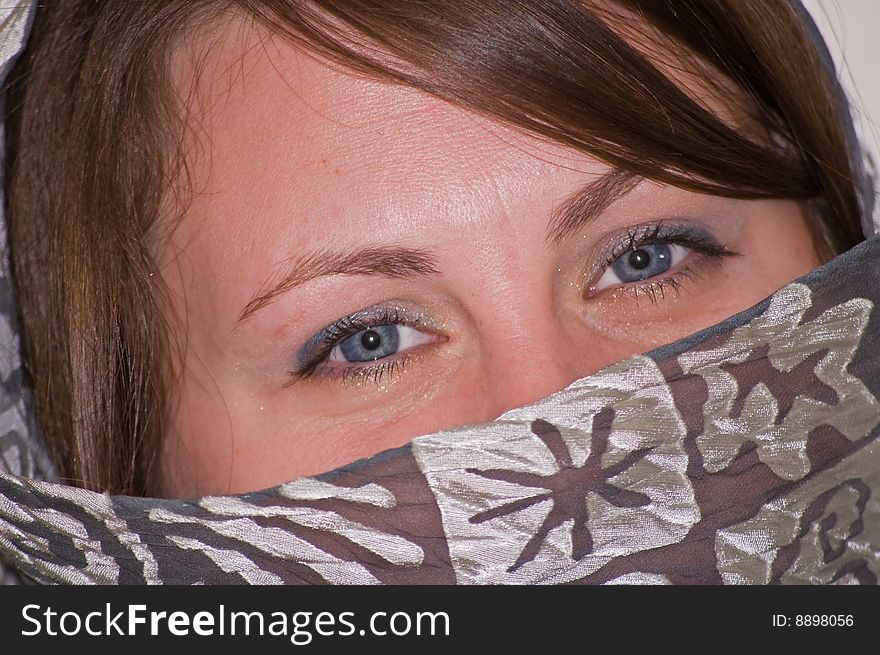 A closeup photo of a Caucasian young woman's lovely blue eyes, made mysterious by the draping of a gray scarf over her face. A closeup photo of a Caucasian young woman's lovely blue eyes, made mysterious by the draping of a gray scarf over her face.