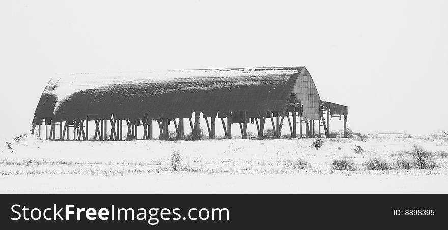 Ramshackle hangar over white background. Winter view