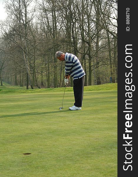 Male golfer putting on the green