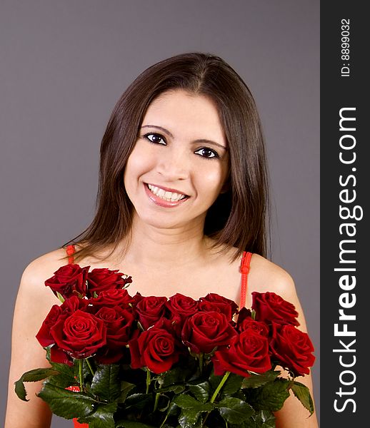 A beautiful young woman is standing with a large bouguet of red roses in front of her. A beautiful young woman is standing with a large bouguet of red roses in front of her.