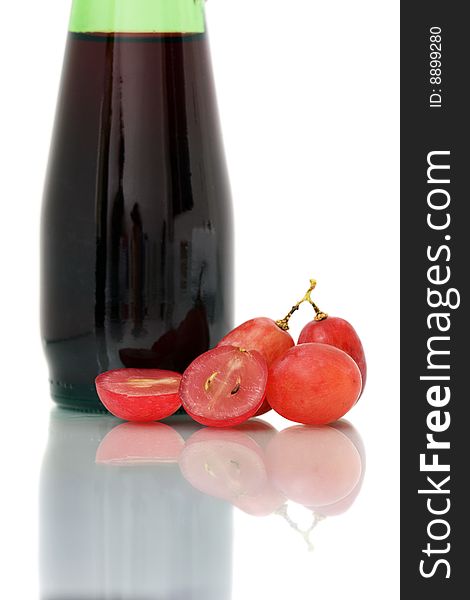 Bunch of red grapes on white plate beside wine bottle. Bunch of red grapes on white plate beside wine bottle.