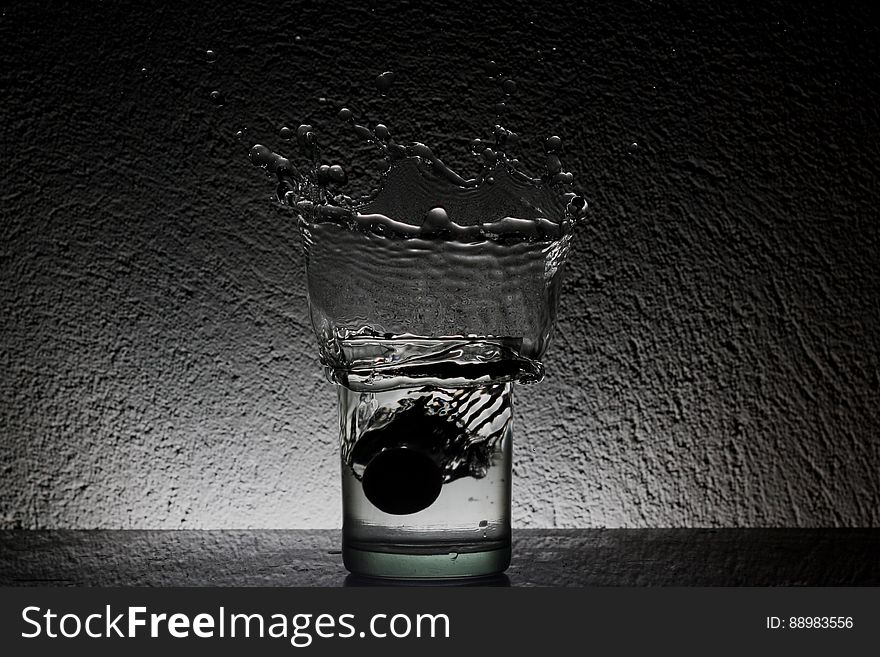 A glass of water with water splashing up.