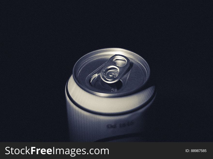 Closeup of the top of an aluminium drinks can showing the pull tab (mechanism) used to open the can, black background. Closeup of the top of an aluminium drinks can showing the pull tab (mechanism) used to open the can, black background.