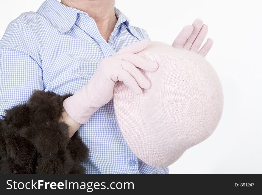 Lady's hands holding a pink hat, wearing pink gloves