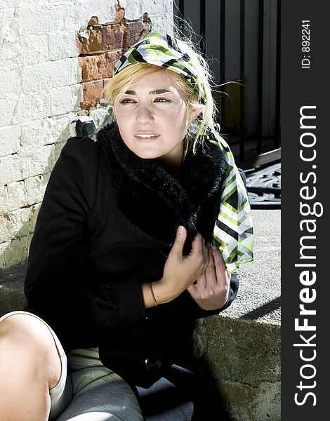 Young Trendy Caucasian Woman Sitting in the Sun on a Cold Day. Young Trendy Caucasian Woman Sitting in the Sun on a Cold Day