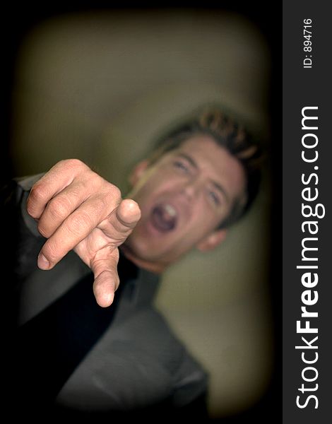 Business Man points with look of disbelief on his face with a gray shirt, black tie, and tan background