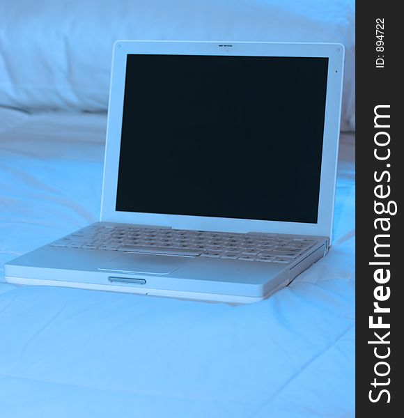 White laptop on top of bed. White laptop on top of bed