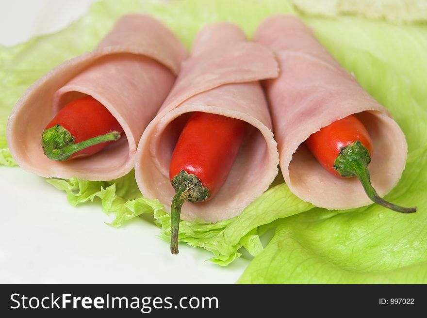 Three chilies wrapped in ham on lettuce. Three chilies wrapped in ham on lettuce