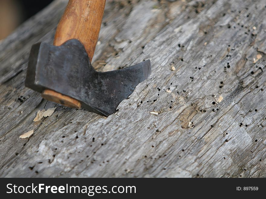 An axe buried into a piece of lumber, waiting to be carved into shape by carpenter. An axe buried into a piece of lumber, waiting to be carved into shape by carpenter