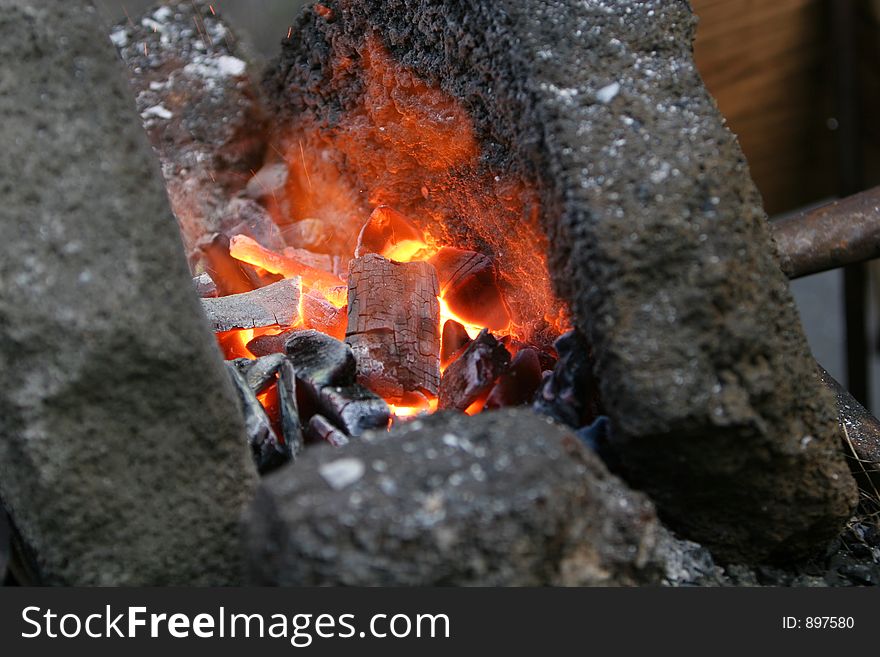 A craftsman/blacksmith working metal the oldfashioned way, with hammer and anvil and open fire. A craftsman/blacksmith working metal the oldfashioned way, with hammer and anvil and open fire