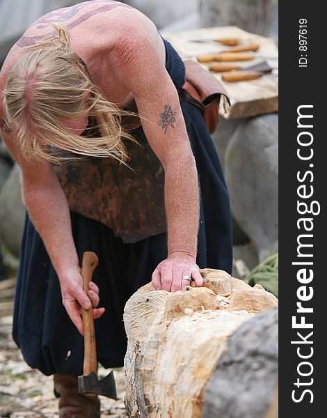 A craftsman working wood the oldfashioned way, using axe to form a figure out of lumber. A craftsman working wood the oldfashioned way, using axe to form a figure out of lumber