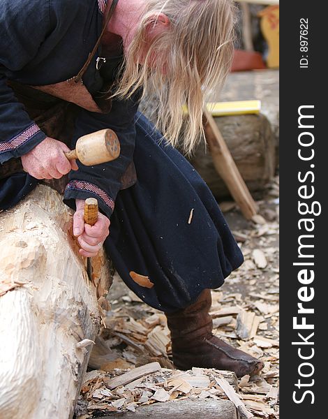 A craftsman working wood the oldfashioned way, chipping away and molding a figure out of a big piece of wood. A craftsman working wood the oldfashioned way, chipping away and molding a figure out of a big piece of wood