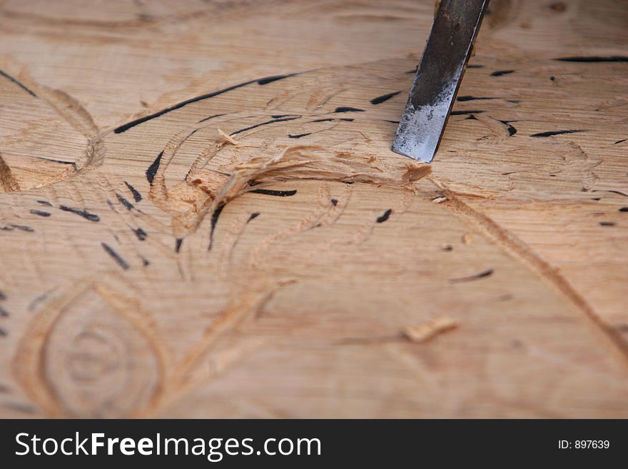 A craftsman working wood the oldfashioned way, chisel being used to carve image into wood. A craftsman working wood the oldfashioned way, chisel being used to carve image into wood