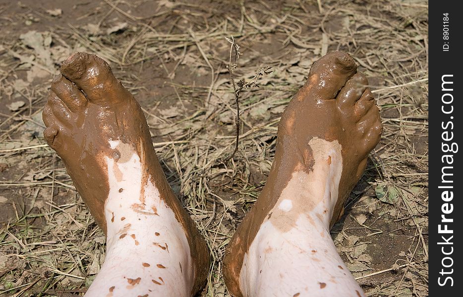 Two muddy feet over dirty grass background. Two muddy feet over dirty grass background