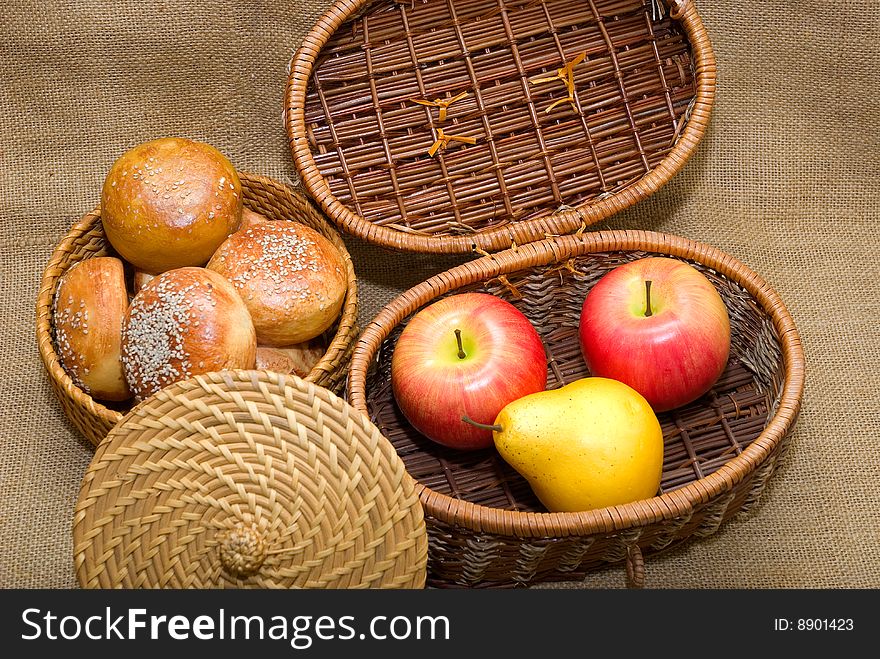 Baskets with rolls and fruits are photographed on an old fabric