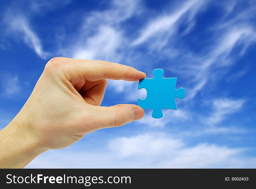 Puzzle in hand isolated on sky background