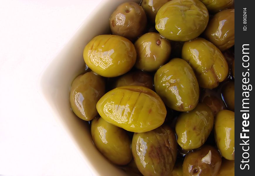 A white bowl full of delicious green olives