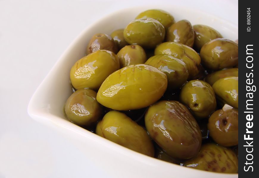 A white bowl full of delicious green olives