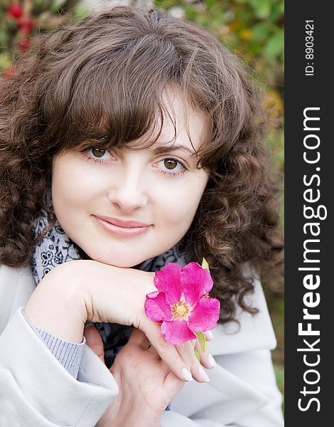 Picture of beautiful girl on a background of flowers and fruits dogrose