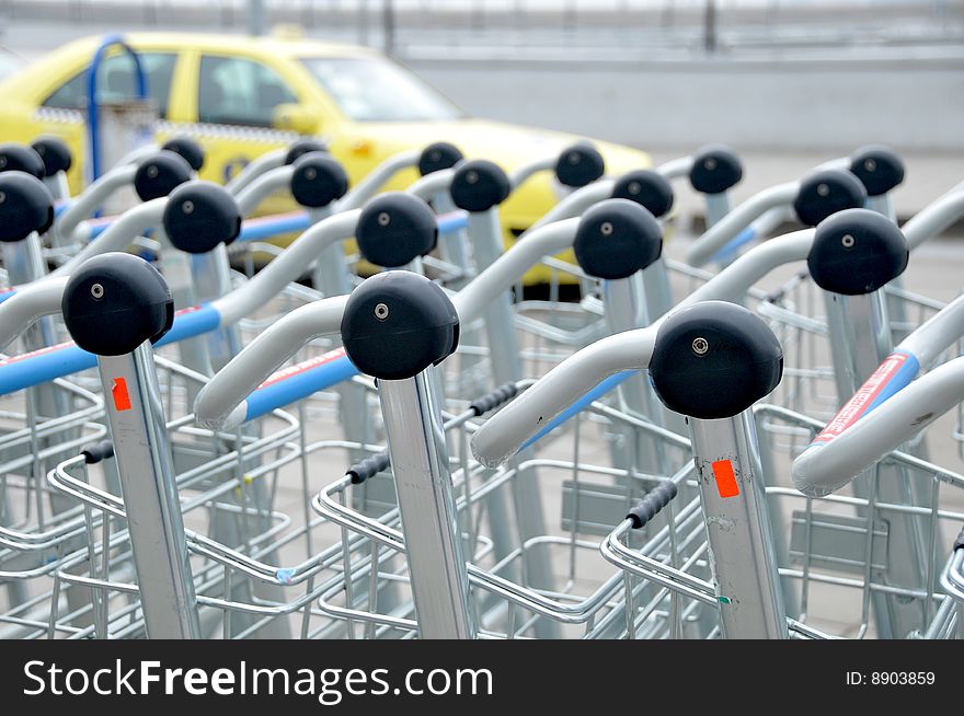 Luggage carts at  international airport. Yellow taxi on the background