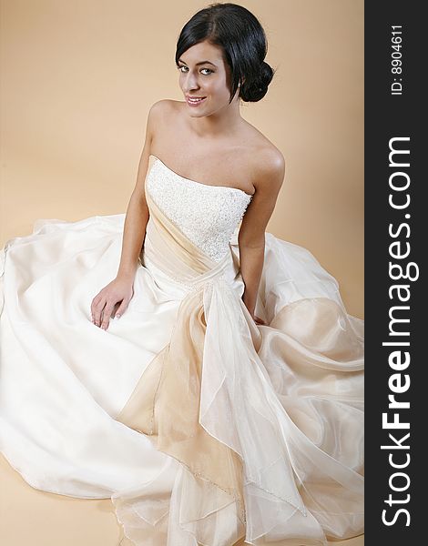 Black haired beauty with hair in bun sitting for wedding fashion portrait.