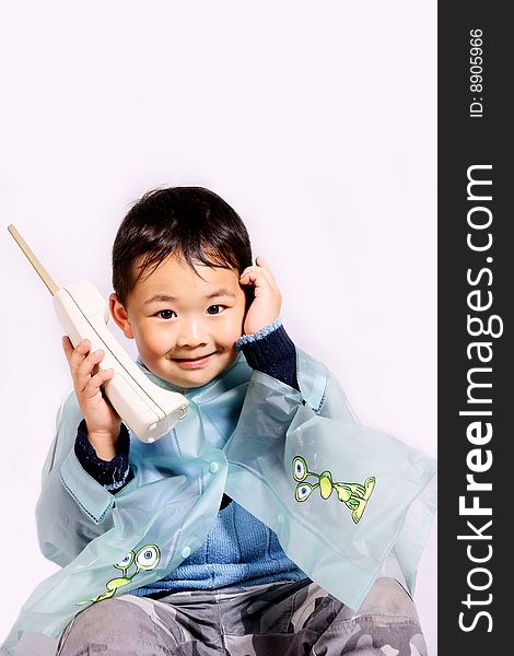 A picture of a little chinese boy holding a telephone in raincoat. A picture of a little chinese boy holding a telephone in raincoat