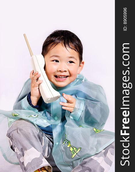 A picture of a little chinese boy holding a telephone in raincoat. A picture of a little chinese boy holding a telephone in raincoat