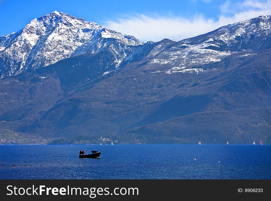 Lake by boat and snow-capped mountains