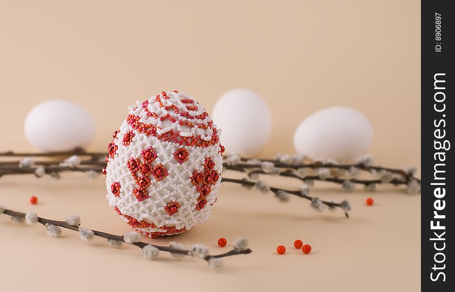 Bead easter egg and sprigs of pussy-willow on a beige background. Bead easter egg and sprigs of pussy-willow on a beige background