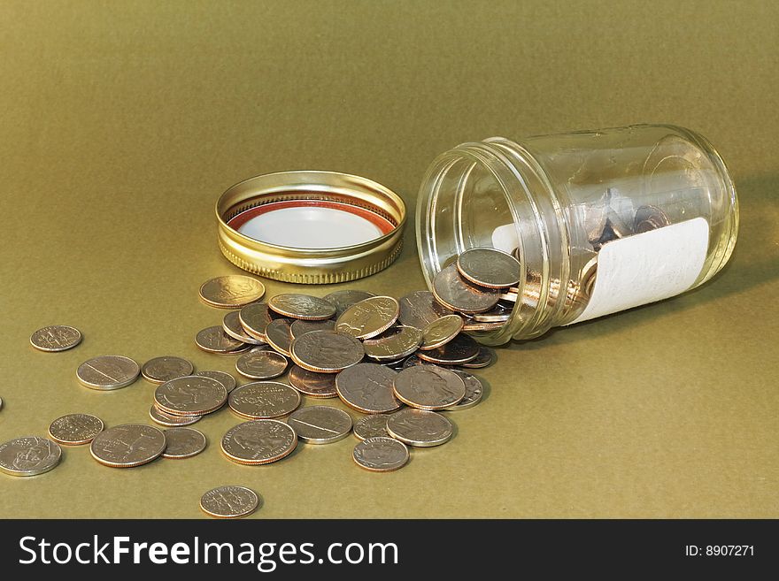 A jar of coins which appears to be knocked over spilling it's contents for access. A jar of coins which appears to be knocked over spilling it's contents for access