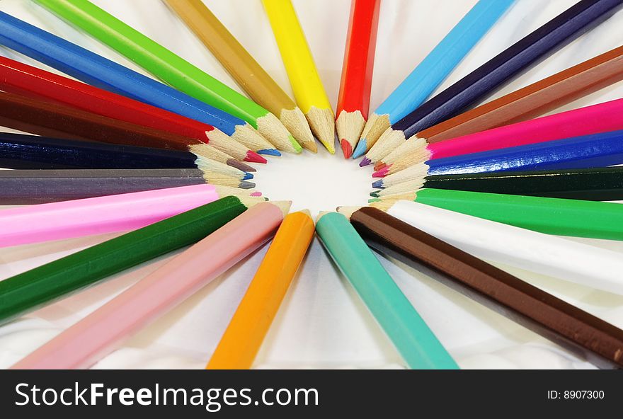 A circle of colored pencils forming a pinwheel of colors. A circle of colored pencils forming a pinwheel of colors