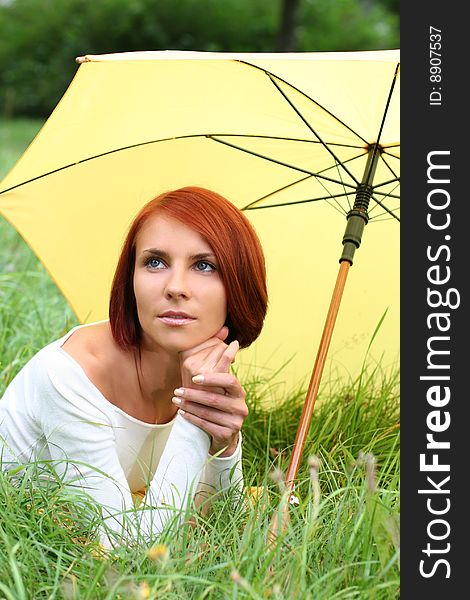 Beautiful girl relaxing on grass under yellow umbrella. Beautiful girl relaxing on grass under yellow umbrella