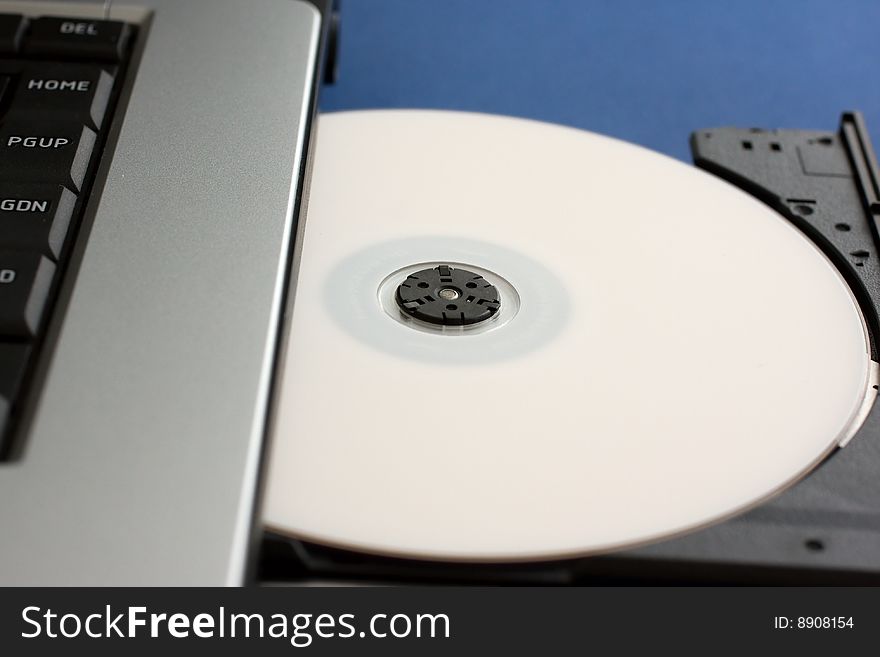 CD or DVD being loaded into Laptop computer indicating piracy or home movie and music creation. CD or DVD being loaded into Laptop computer indicating piracy or home movie and music creation