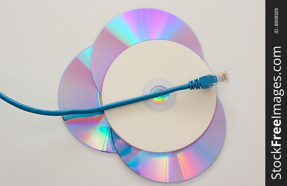 Blue Ethernet cable running over blank DVD or CD symbolizing data piracy. Blue Ethernet cable running over blank DVD or CD symbolizing data piracy