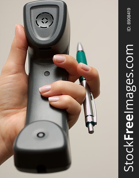 Business telephone in hand with a pen