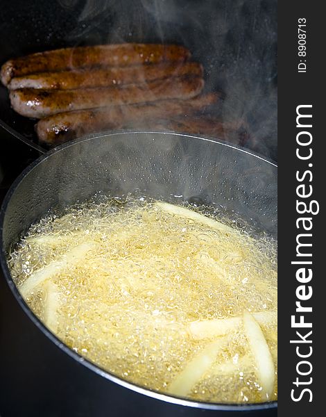Image of French fries and sausages being prepared.