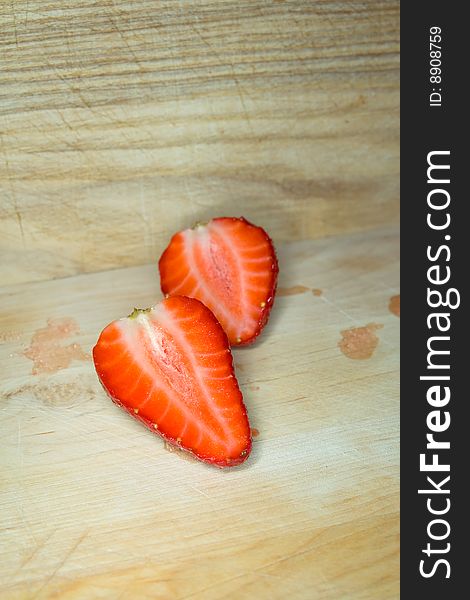 Two strawberry halves on a wooden cutting board. Two strawberry halves on a wooden cutting board.