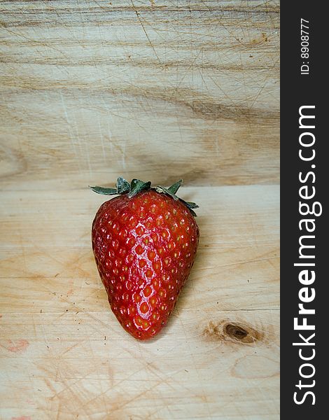 Macro image of a strawberry on a wooden cutting board. Macro image of a strawberry on a wooden cutting board.