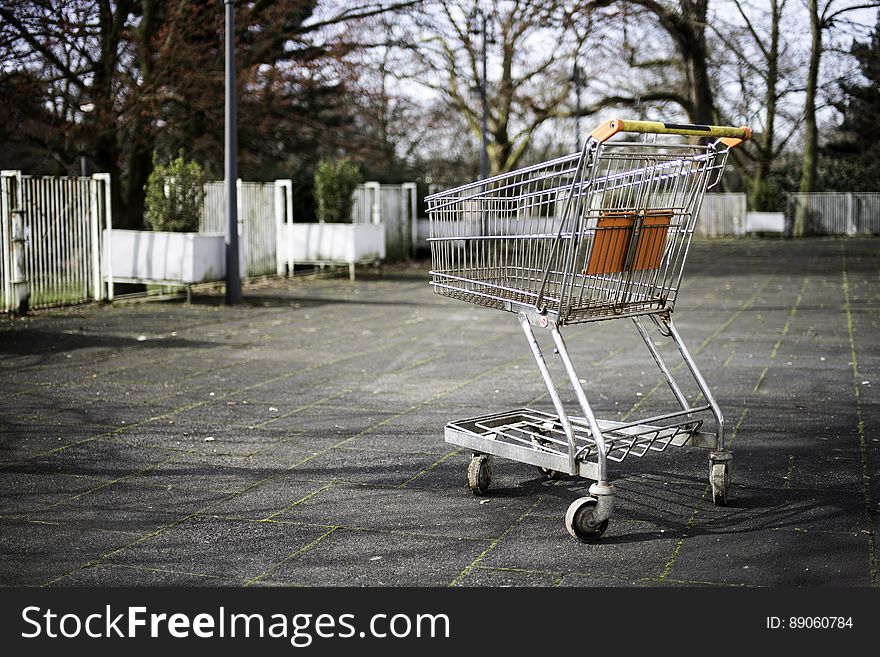 An empty shopping trolley on a pavement.