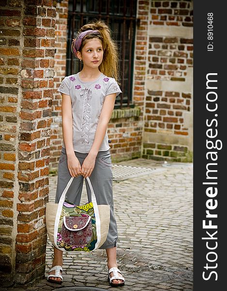 Trendy fashion teenager girl showing off new clothes and shopping bag against street background
