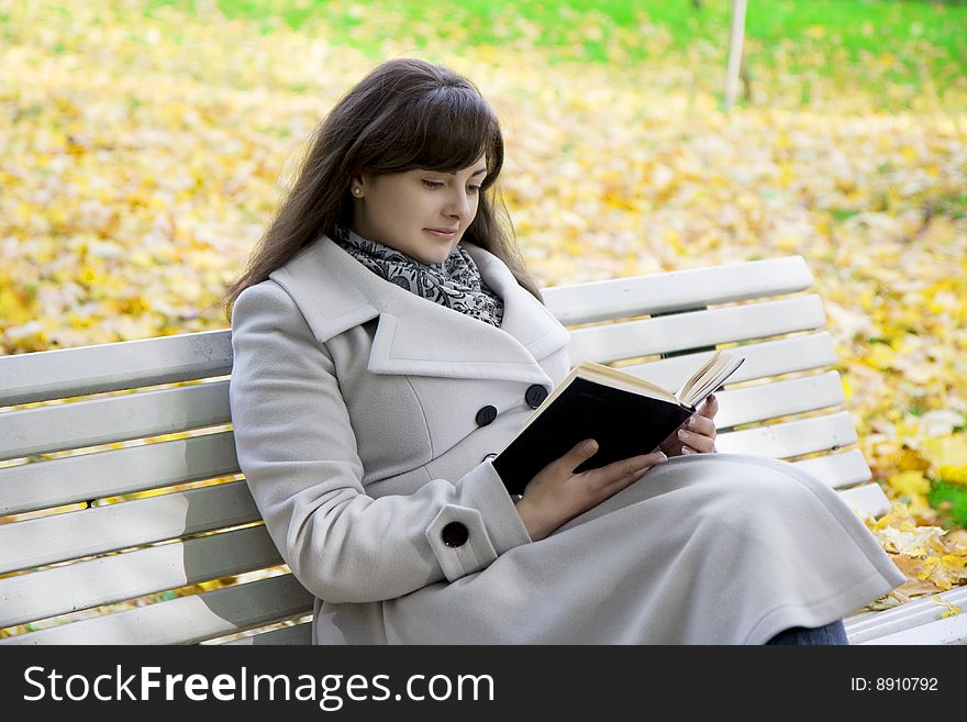 Picture of a girl who reads the book in the park on a bench