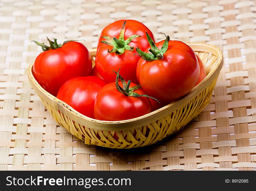 Fresh tomato in a basket  on bamboo chip mat  background. Fresh tomato in a basket  on bamboo chip mat  background