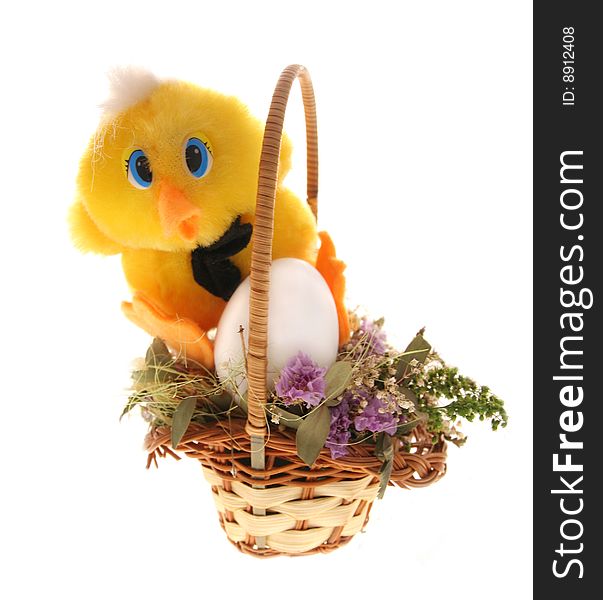 Toy chicken sits near the egg in the basket filled with small dry flowers and looks directly. Toy chicken sits near the egg in the basket filled with small dry flowers and looks directly