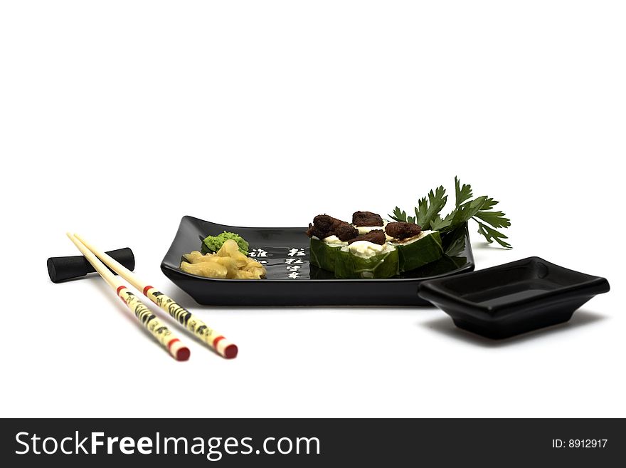 A set of sushi on a black plate with wasabi and gari, isolated on a white background, wish hashi ans soy sauce. A set of sushi on a black plate with wasabi and gari, isolated on a white background, wish hashi ans soy sauce.