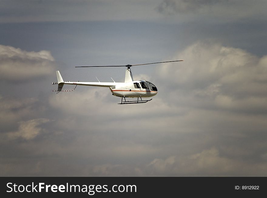 A four passenger helicopter flying through a cloudy sky. A four passenger helicopter flying through a cloudy sky.