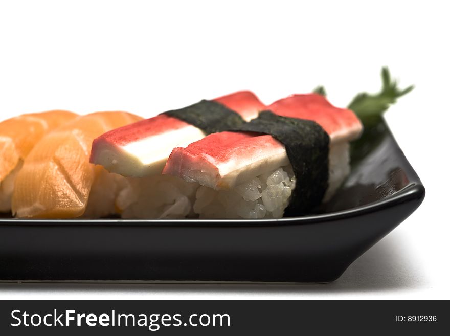 A set of sushi on a black plate with wasabi and gari, isolated on a white background, close-up. A set of sushi on a black plate with wasabi and gari, isolated on a white background, close-up.