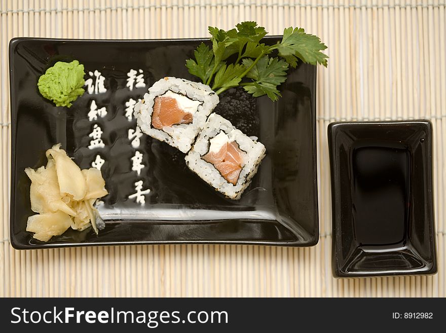 A set of sushi on a black plate with wasabi and gari, on a makisu (bamboo rolling mat). A set of sushi on a black plate with wasabi and gari, on a makisu (bamboo rolling mat).